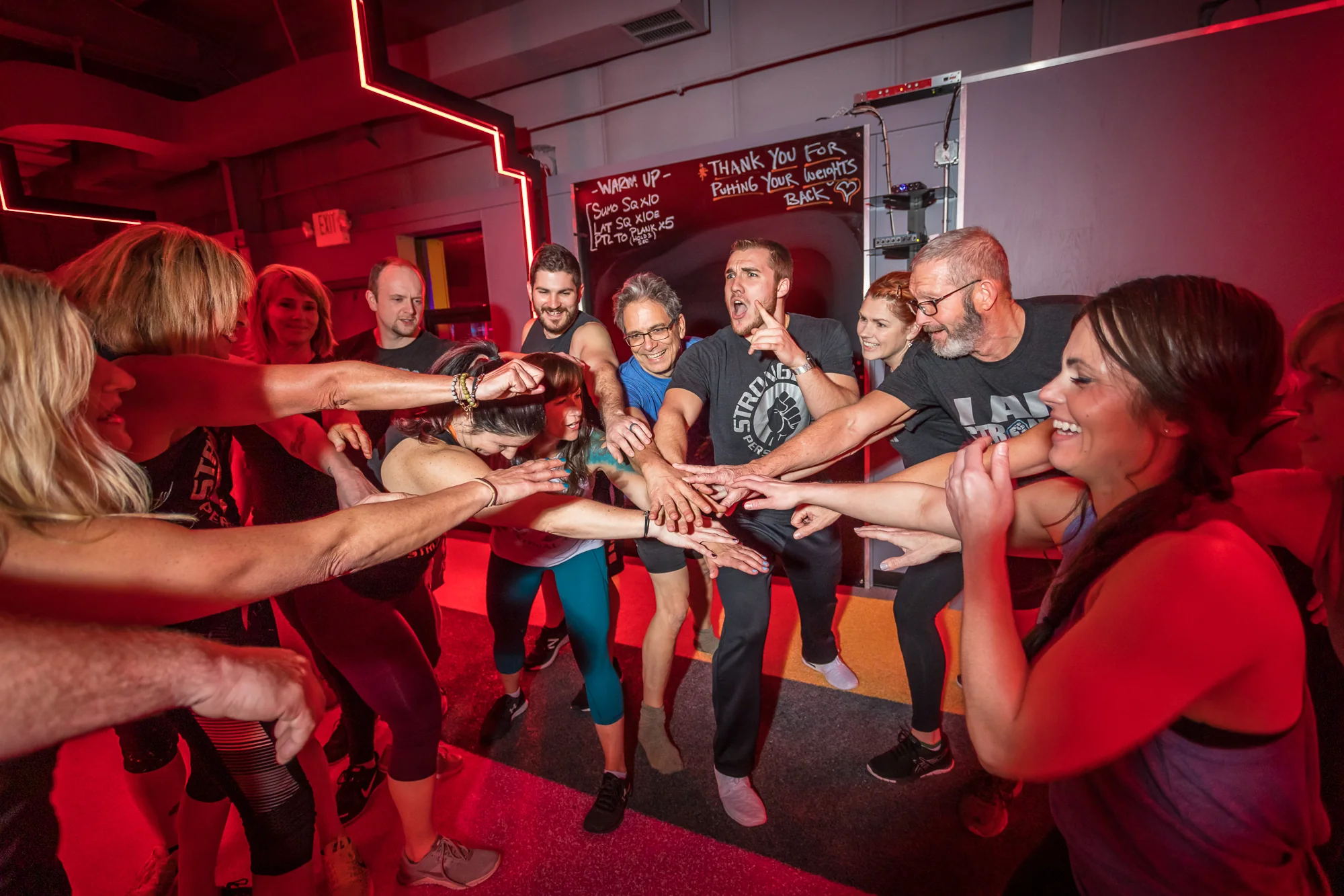 Smiling Stronger members bringing their hands together after a group workout.
